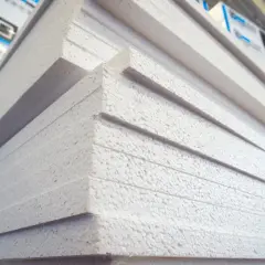 Stos białych płyt styropianowych ułożonych w stos.